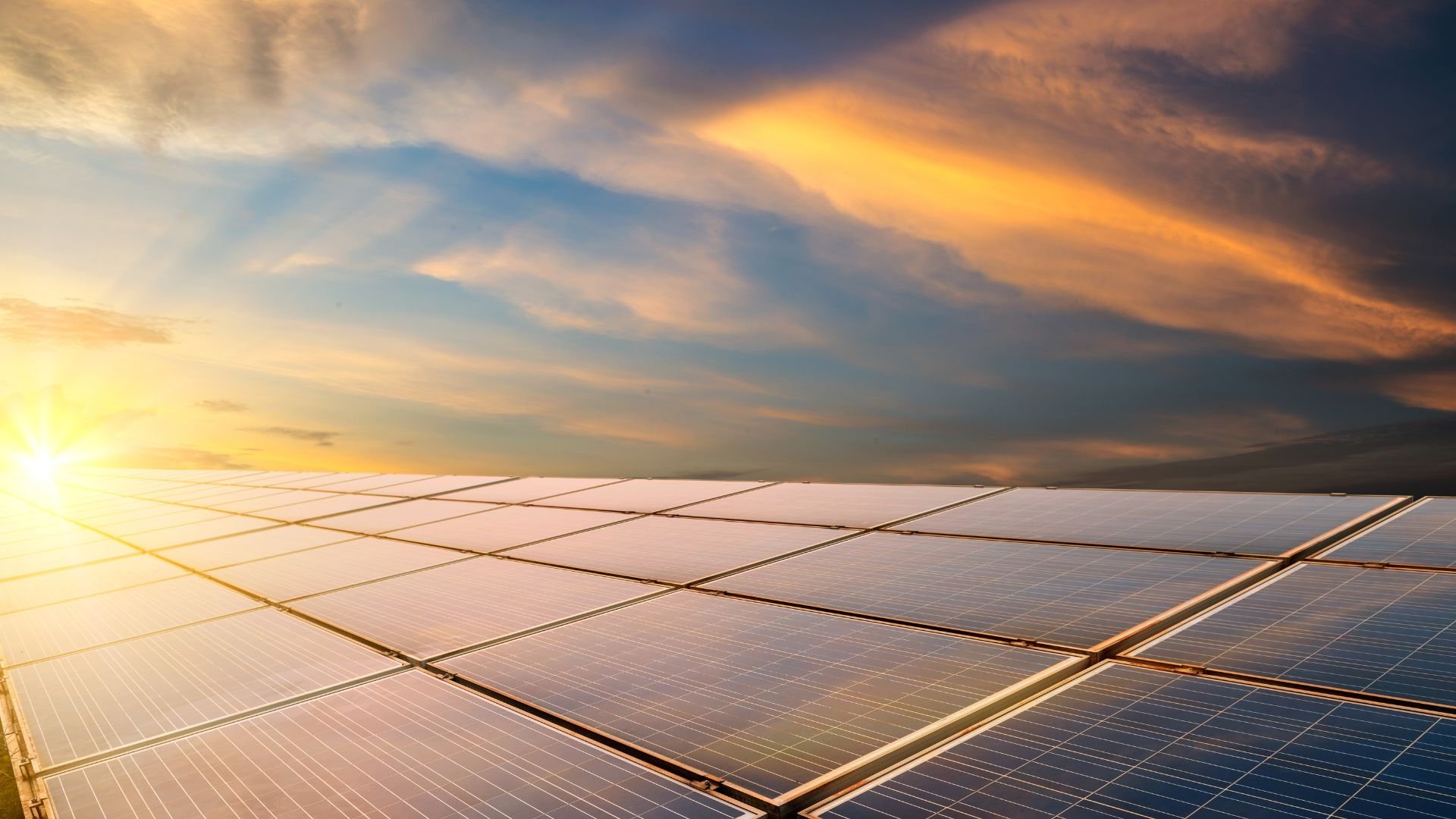 Solar panels array under dramatic sunset sky with glowing sunlight